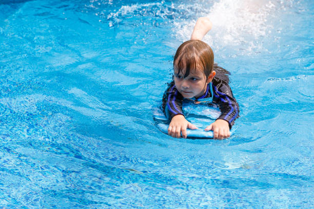 istock little boy learning to swim in pool, practicing with foam pad 851964758