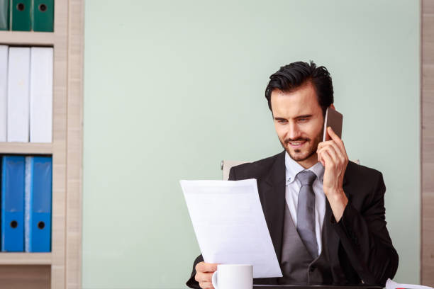istock Young business man with document and smartphone in his hand at modern office room 851965244