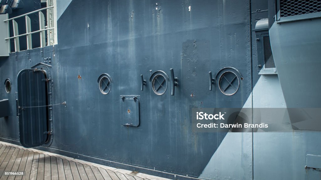 Ship Portholes Three portholes looking out onto the deck of an elderly ship. Battleship Stock Photo