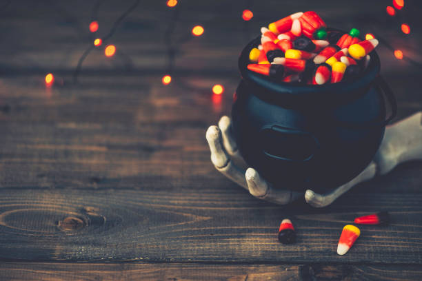 istock Halloween background with cauldron, candy and skeleton hand 851971382