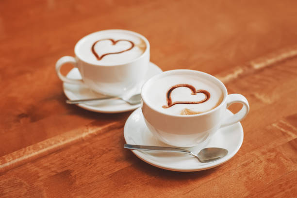 istock Latte art coffee cups with hearts on table in cafe 851977930