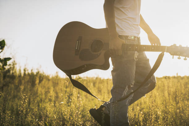 istock low section of man walking in field with guitar 851994092