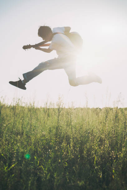 istock young powerful man jumping in field with guitar 851995774