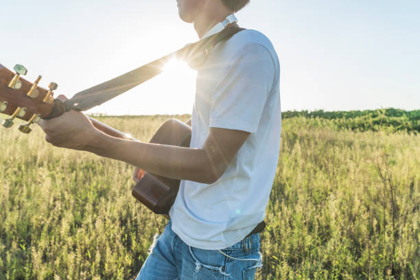 istock young asian man playing guitar in field 851996818