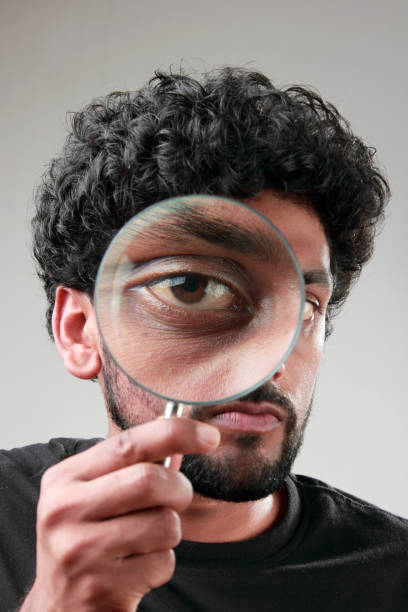 istock Enlarged eyes of a young man looking through a magnifying glass 852000310