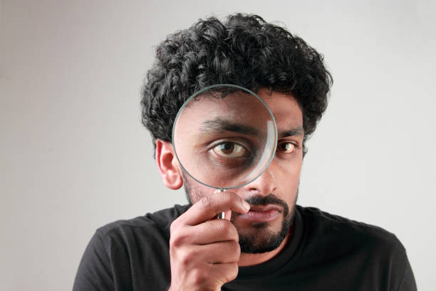 istock Enlarged eyes of a young man looking through a magnifying glass 852000322