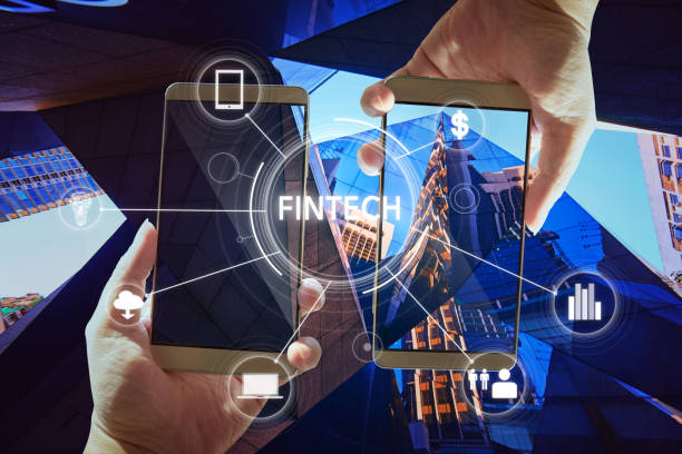 "Fintech" word on digital virtual screen with two businessman hands holding smartphones background. stock photo