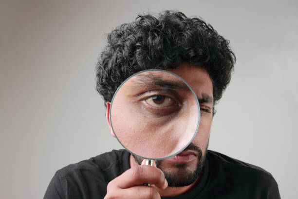 istock Enlarged eyes of a young man looking through a magnifying glass 852000670