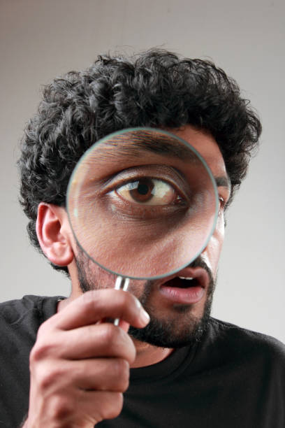 istock Enlarged eyes of a young man looking through a magnifying glass 852000696