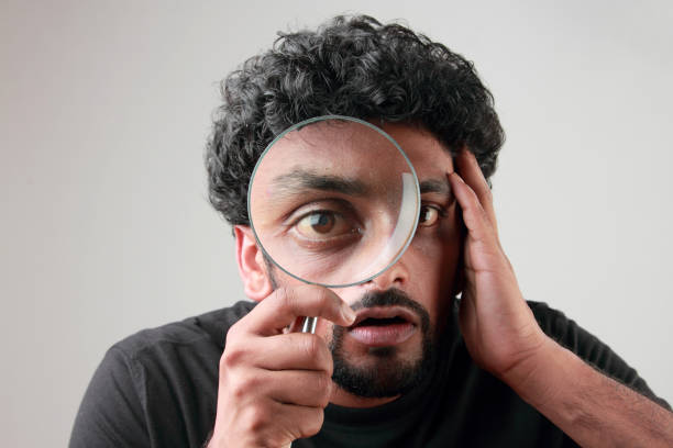 istock Enlarged eyes of a young man looking through a magnifying glass 852001910