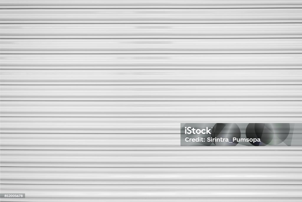 The texture of corrugated metal sheet, white or gray galvanizes steel rolling shutter. Door Stock Photo
