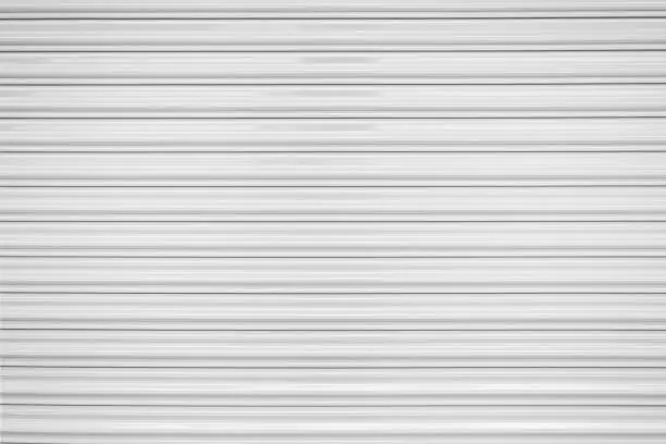 Photo of The texture of corrugated metal sheet, white or gray galvanizes steel rolling shutter.