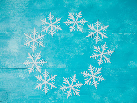 Christmas background with snowflakes on wooden board. View from above. Flat lay