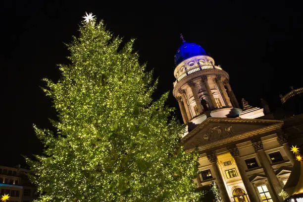 Berlin, Germany: An illuminated christmas tree at a christmas-market in front of a church.