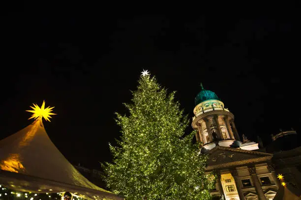 Berlin, Germany: An illuminated christmas tree at a christmas-market in front of a church.