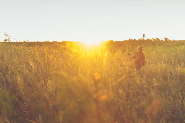 young asian woman playing guitar in field against sunbeam.