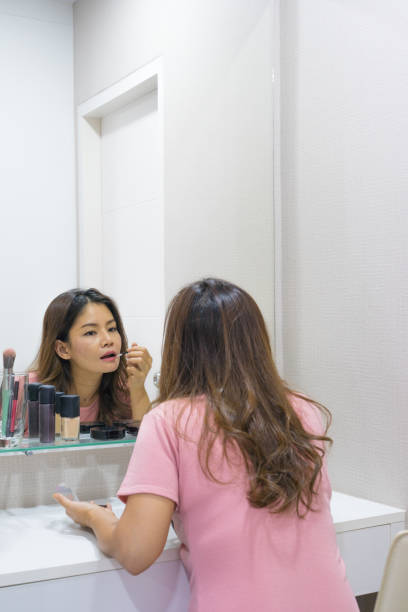 istock Asian woman applying red lip brush in mirror 852021700