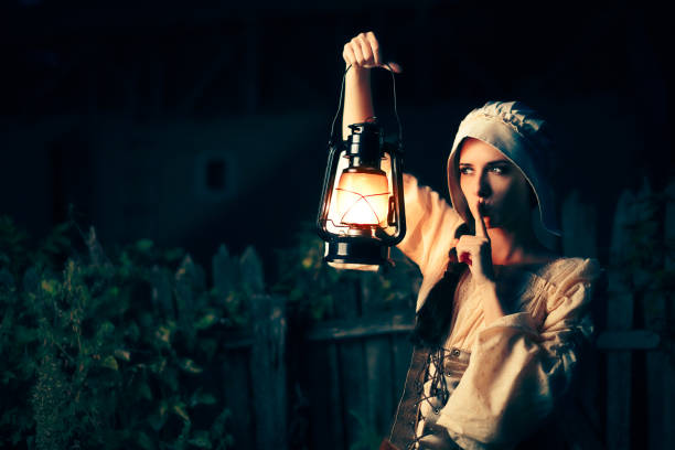 donna medievale con il dito sulle labbra che tiene una lampada - victorian style women dress night foto e immagini stock