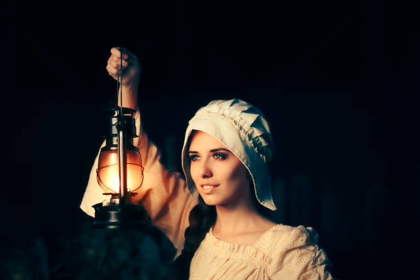 Medieval Woman with Vintage Lantern Outside at Night Cosplay girl in Halloween costume holding a lamp bonnet hat stock pictures, royalty-free photos & images