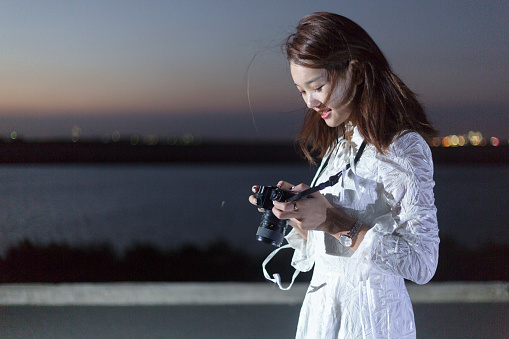 beautiful woman photographing at urban waterfront,china.