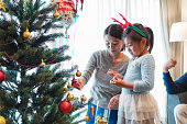 クリスマス ツリーを飾る彼女のお母さんを手伝って若い女の子