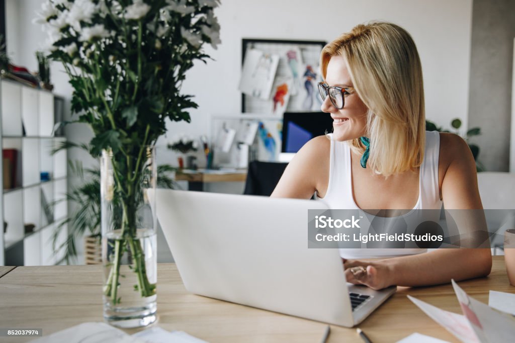 fashion designer using laptop beautiful smiling young fashion designer using laptop at workplace Fashionable Stock Photo