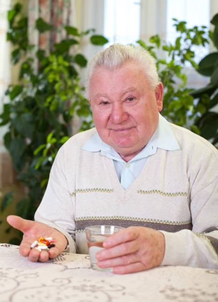 Elderly man holding pills and water