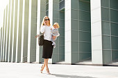 Successful business mother in city with baby in her hands