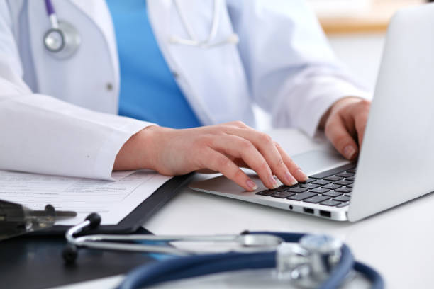 istock Close up of unknown female doctor typing on laptop computer while sitting  at the table 852048858