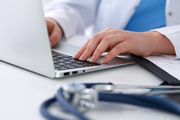 istock Close up of unknown female doctor typing on laptop computer while sitting  at the table 852048968