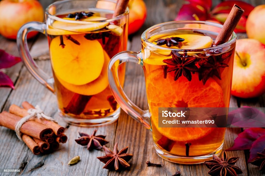 Hot mulled apple cider with cinnamon sticks, cloves and anise Hot mulled apple cider with cinnamon sticks, cloves and anise on wooden background Tea - Hot Drink Stock Photo