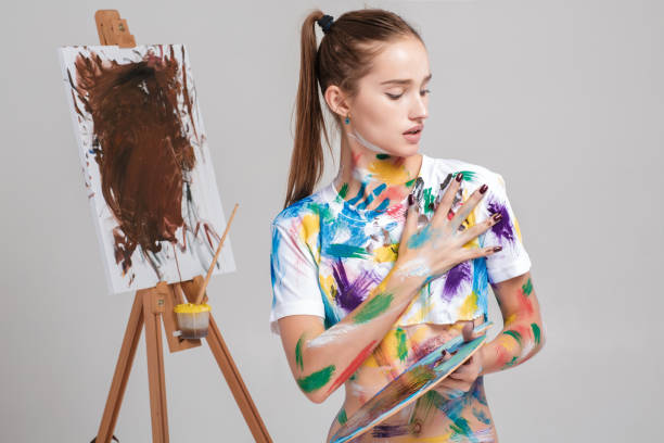 istock woman painter soiled in colorful paint draws on canvas. 852067566
