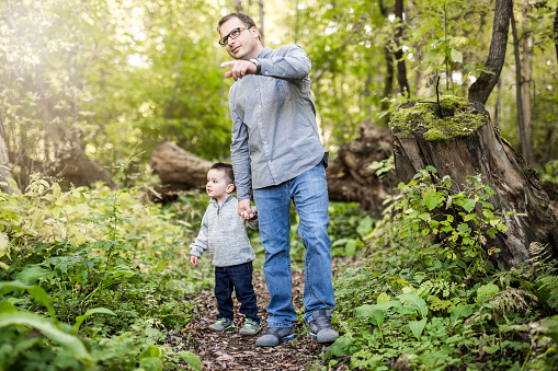 A Little boy and his father on grass in autumn forest