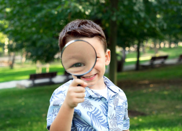 istock Little caucasian boy is looking through magnifying glass 852088364