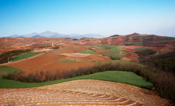 Brown sand agriculture landscape at midday with mountains and green hills at the background and nobody around, China.