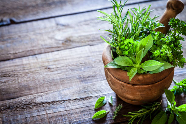 mortar and pastle with fresh herbs for cooking on rustic wooden table - herbal medicine herb alternative medicine medicine imagens e fotografias de stock
