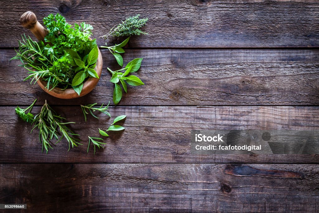 Mortero y pastle con hierbas frescas para cocinar en la mesa de madera rústica - Foto de stock de Herbología libre de derechos