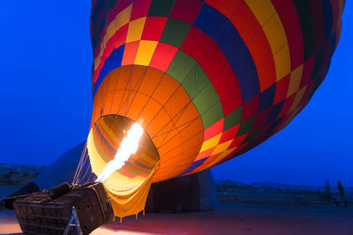 Closeup view of colorful hot air balloon on blue sky background at sunrise. The balloon is flying over Goreme Historical National Park, Cappadocia, Turkey. Cappadocia is a popular tourist destination.