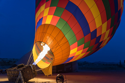 Hot air balloon with bright burning flame flying in the night.