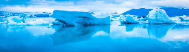 istock Blue icebergs reflecting in tranquil Arctic Ocean lagoon panorama Iceland 852099082