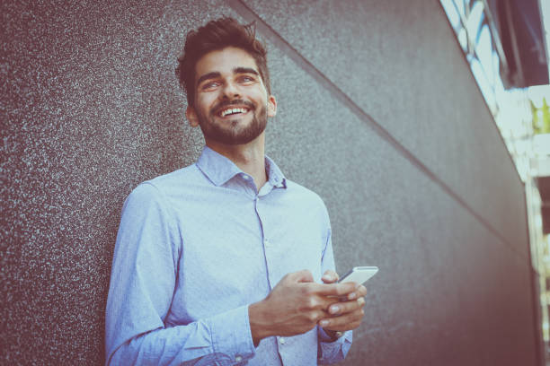 istock Young businessman leaning against wall using smart phone. Space for copy. 852102426