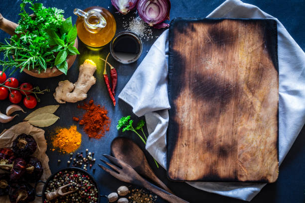 istock Old wooden cutting board with spices and herbs on dark kitchen table 852102546