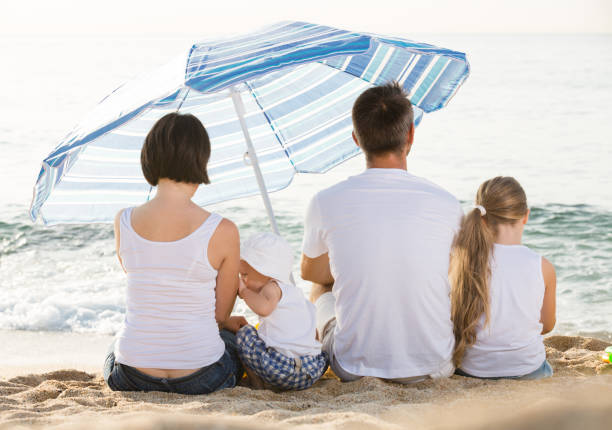 istock back view on family of four sitting on beach 852103264