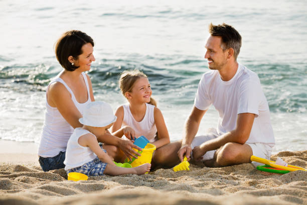 istock Parents with two kids playing with toys on beach 852103296