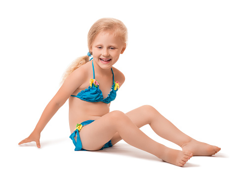 A smiling little blond girl in a swimsuit isolated on white background.
