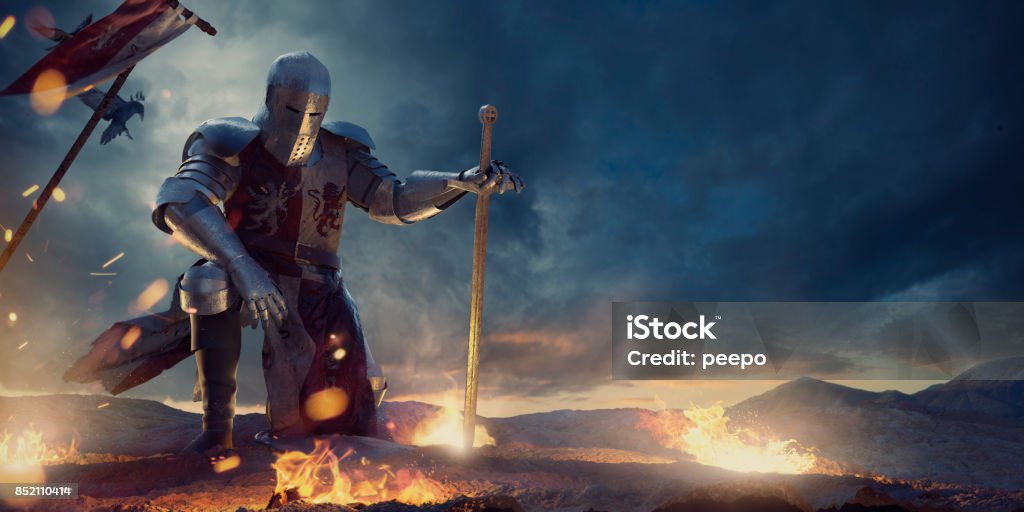 Knight in Amour Kneeling With Sword on Hilltop Near Fire A knight in a full suit of armour, and tabard kneeling with one hand on knee and other resting on sword. The warrior is on rocky high ground surround by small fires of burning debris., with medieval battle flag in the ground behind him, under a dramatic, dark, stormy evening sky. Knight - Person Stock Photo