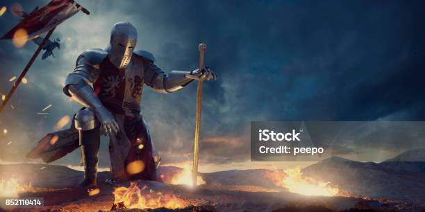 Knight In Amour Kneeling With Sword On Hilltop Near Fire Stock Photo - Download Image Now