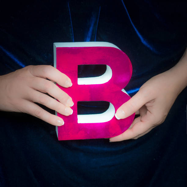 istock Pink painted cardboard letter B in manicured hands 852114264