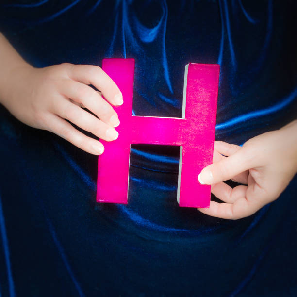 istock Pink painted cardboard letter H in manicured hands 852114374