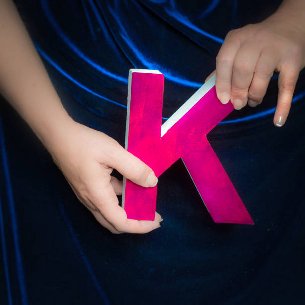 istock Pink painted cardboard letter K in manicured hands 852114452